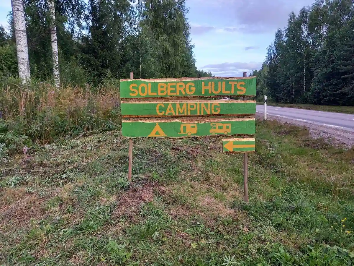 En tältplats på Solberg Hults camping omgiven av gröna träd och gräs, med tält uppställda i en skogsmiljö.