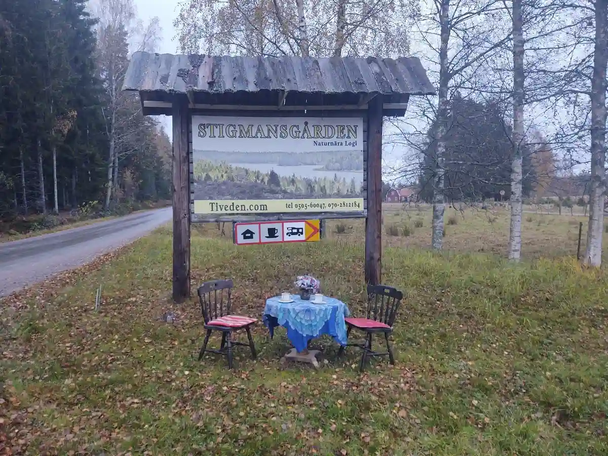 En träskylt i en skogsmiljö som visar vägen till Stigmansgården i Tiveden, omgiven av tät skog.