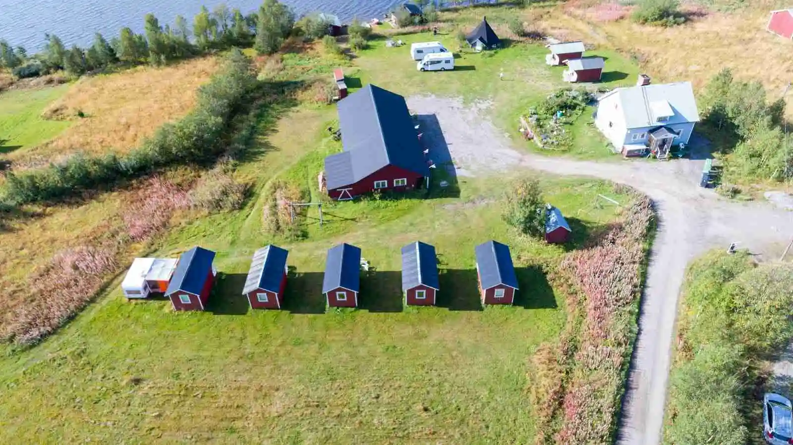 Fågelperspektiv av Piilijärvi camping med pittoreska stugor och öppna grönområden i en lantlig miljö.