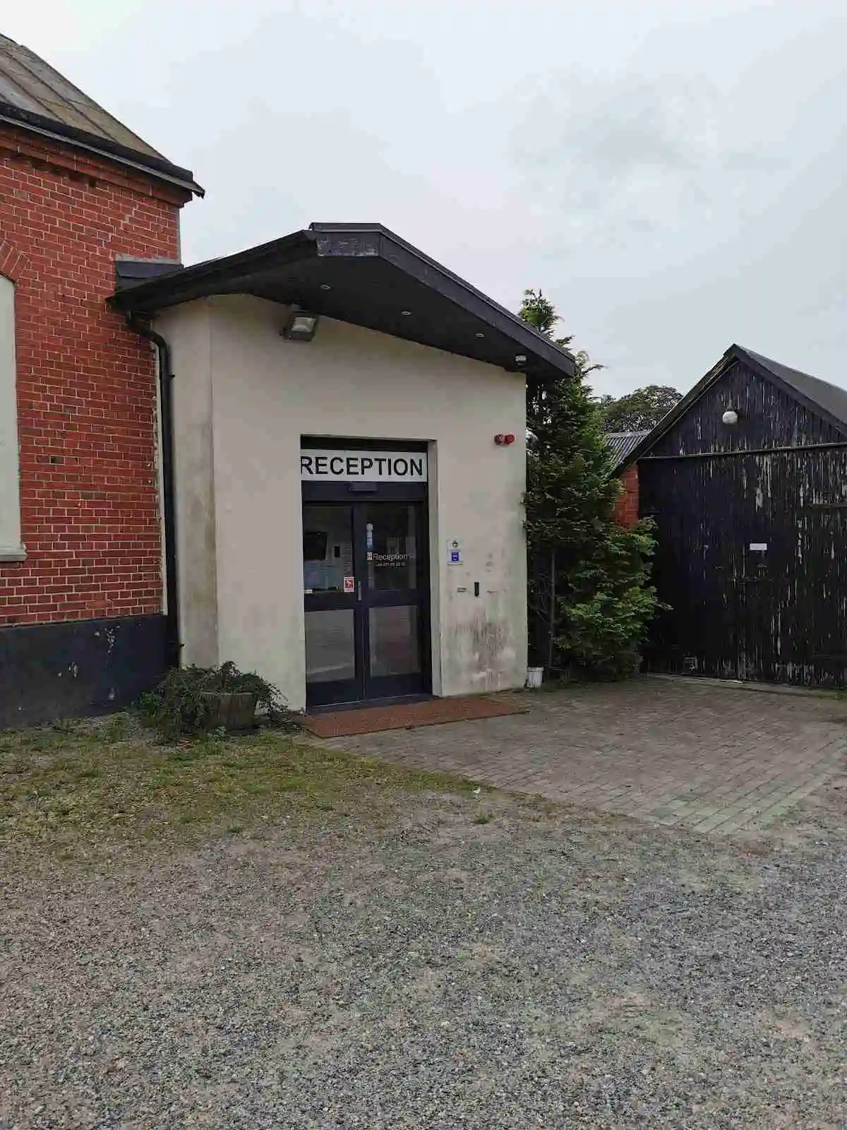 En brun dörr med glasrutor leder in till Fredriksbergs kursgård-camping, i förgrunden syns en asfalterad uppfart.