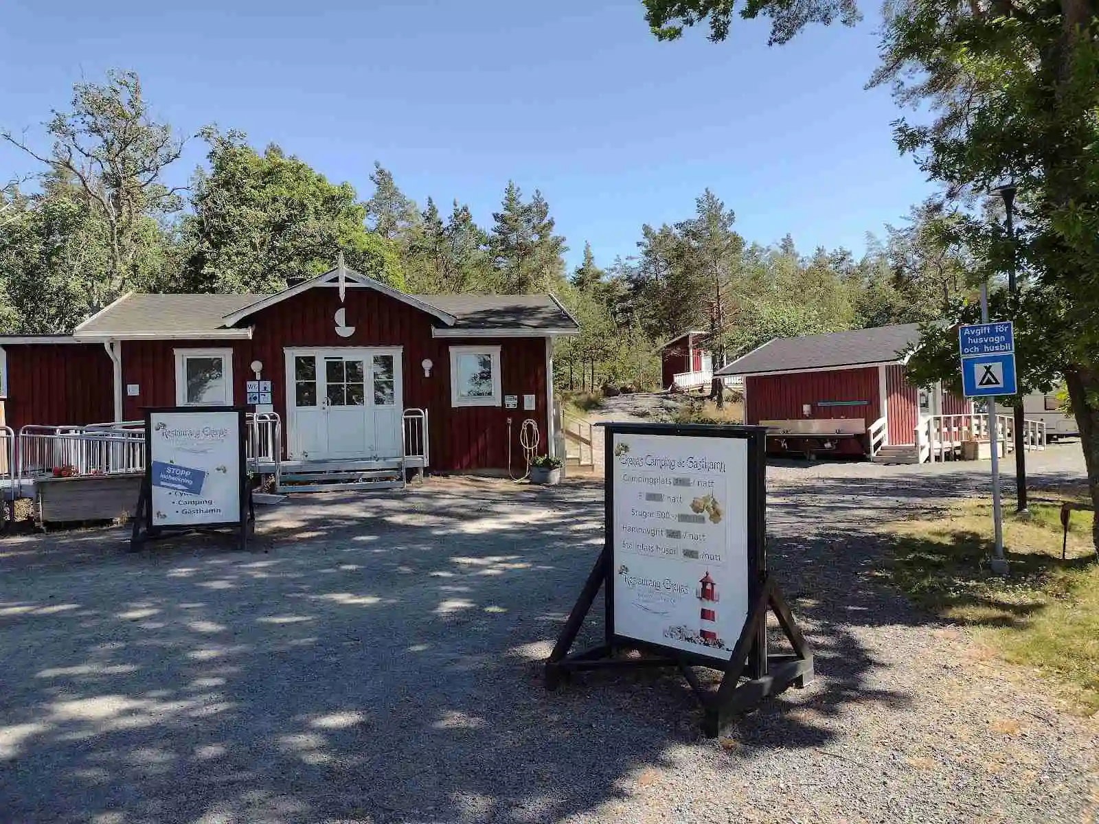 Bild av Ekenäs gästhamn & camping. En trevlig offentlig plats med skugga, utrustad med utemöbler som bildar en inbjudande viloplats i en grönskande trädgårdsmiljö.