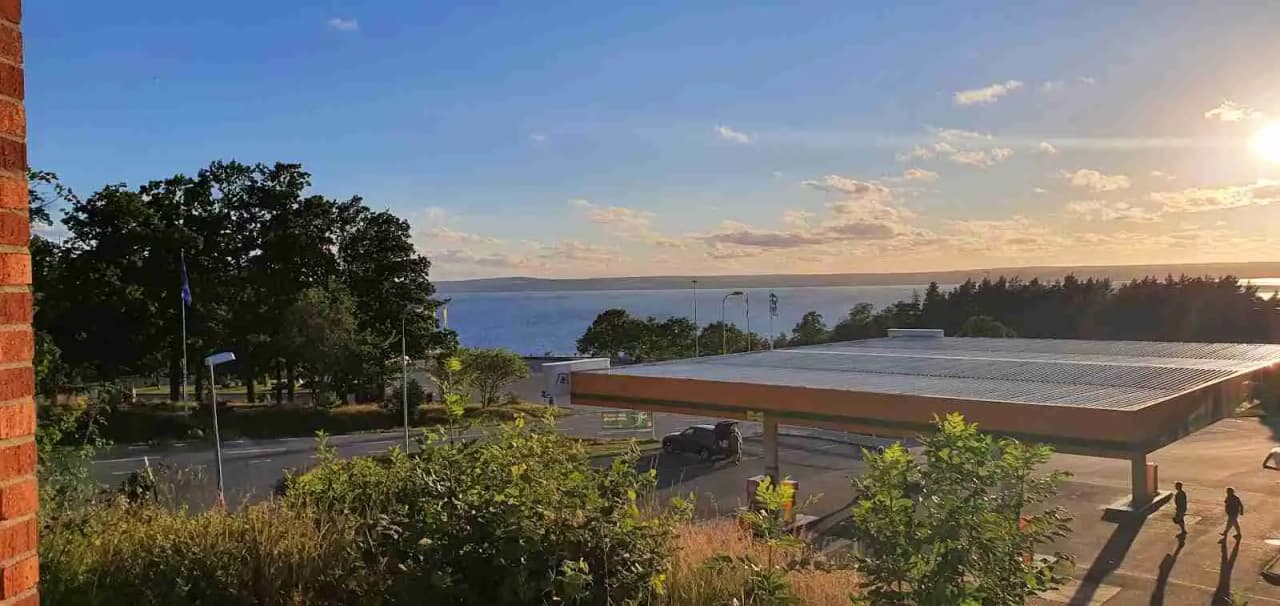 Bild av en campingplats vid Vättersmålen, med en promenadstig som slingrar sig genom området under en delvis molntäckt himmel.