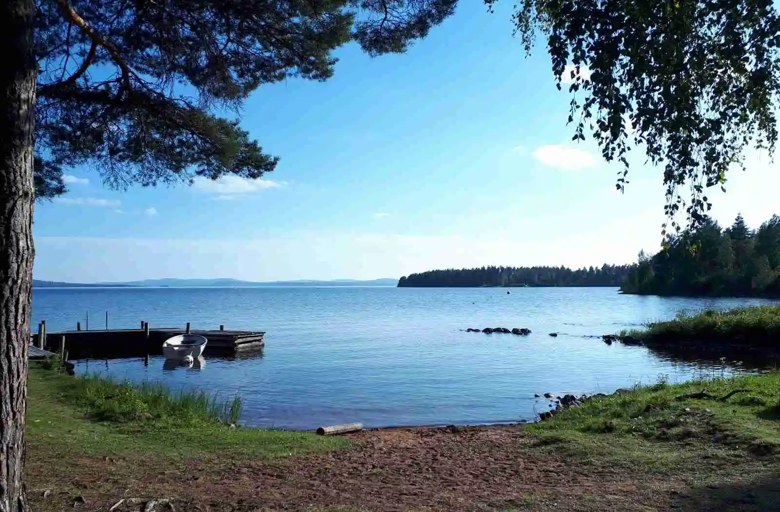 En blå sjö omgiven av grönska vid Vikarbygården, med kustlinjer och naturmiljö i bakgrunden.