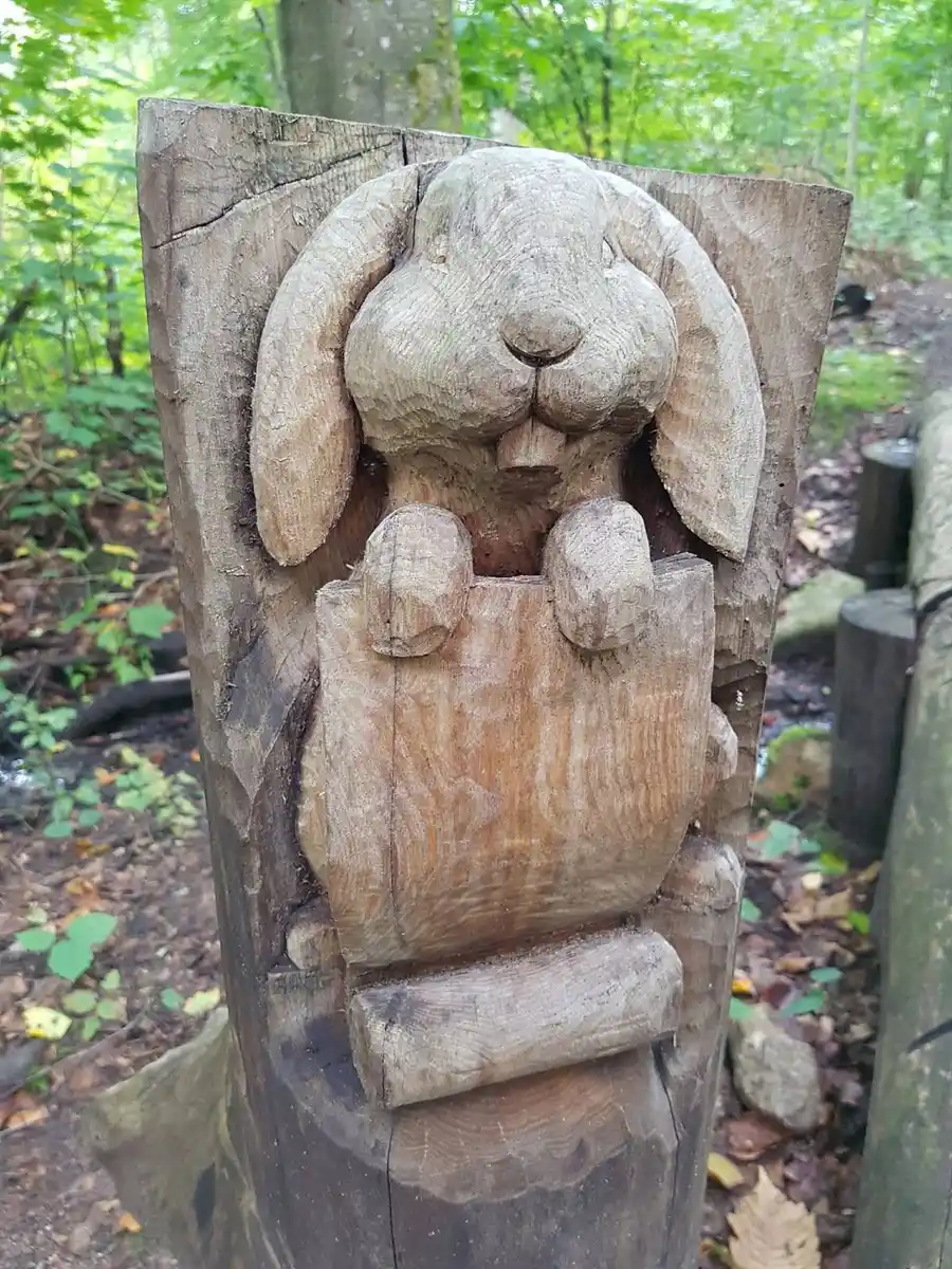 En träskulptur på Elfdalens camping, konstfullt snidad som ett miljökonstverk, placerad på en grön gräsmatta.