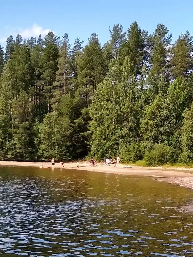 En naturskön campingplats vid vattnet med en flod omgiven av skog.