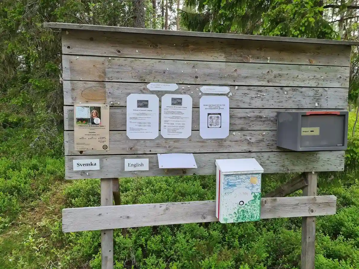 Bild av en skylt vid Storsands camping omgiven av frodig markvegetation i ett naturreservat. En stig syns i bakgrunden.