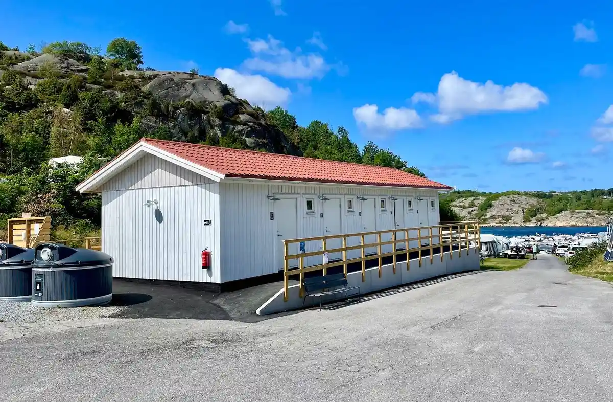 En naturskön vy över Örns camping, belägen vid kusten med utsikt över bukten. I bakgrunden syns den pittoreska semesterorten, omgiven av grönskande natur.
