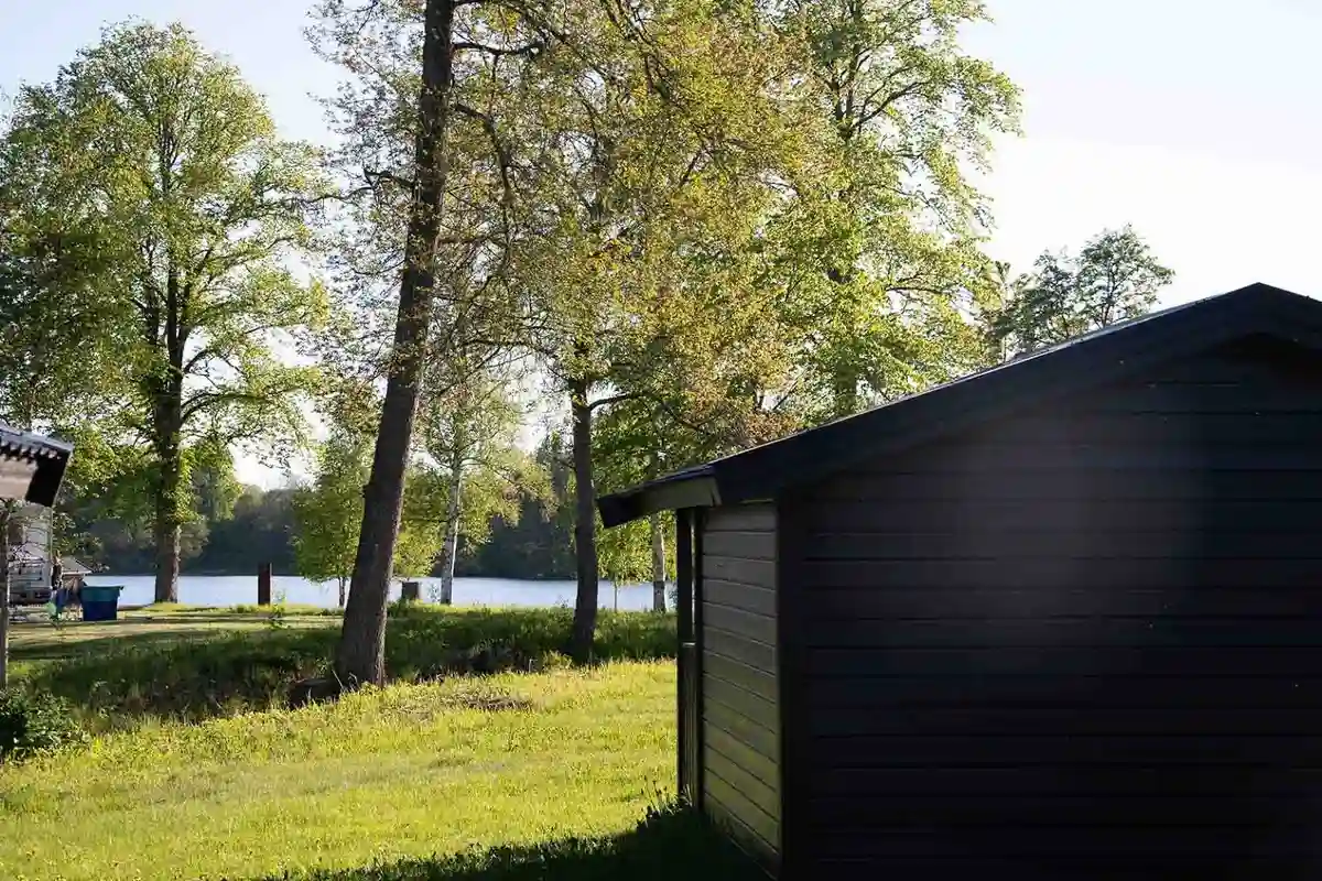 Bild av Valle Cabins: En naturskön miljö med gröna träd och gräsmatta. Stugor och andra trädgårdsbyggnader syns på en solig tomt, vilket skapar en idyllisk, lantlig atmosfär.