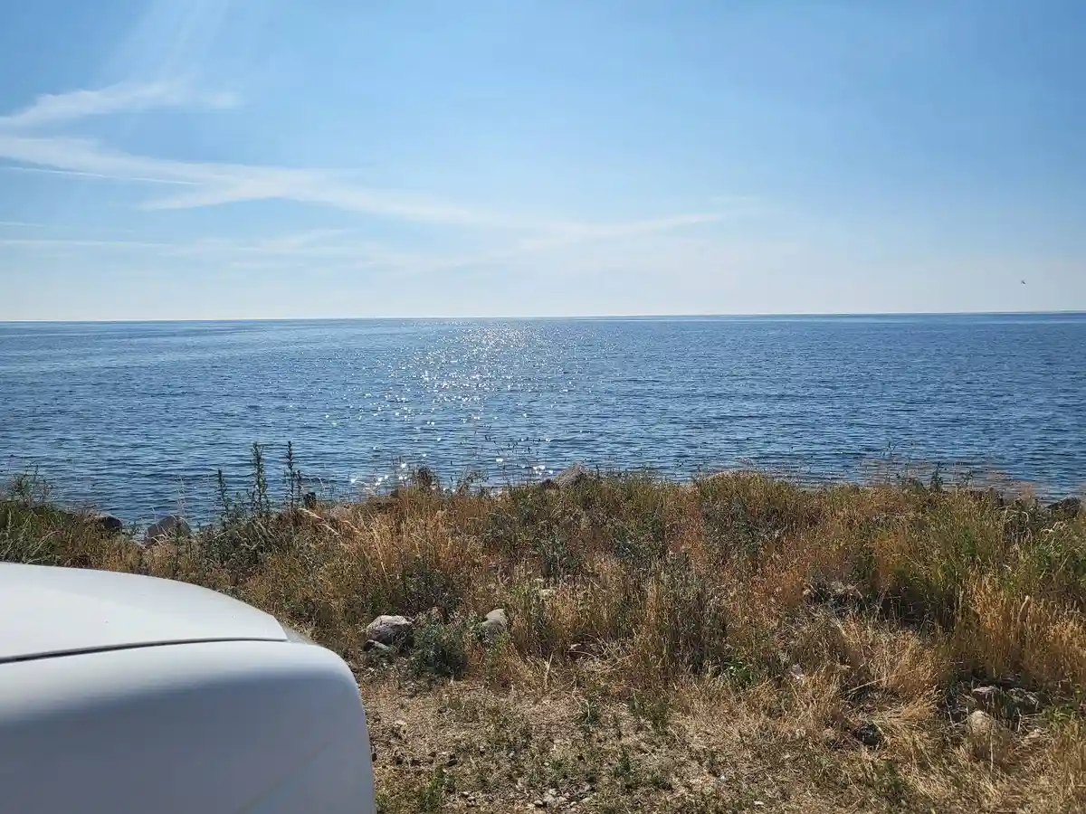 Vy över Valjevikens camping med klarblått hav och horisont i bakgrunden. Soligt sommarväder med kust och vattenresurser i fokus.