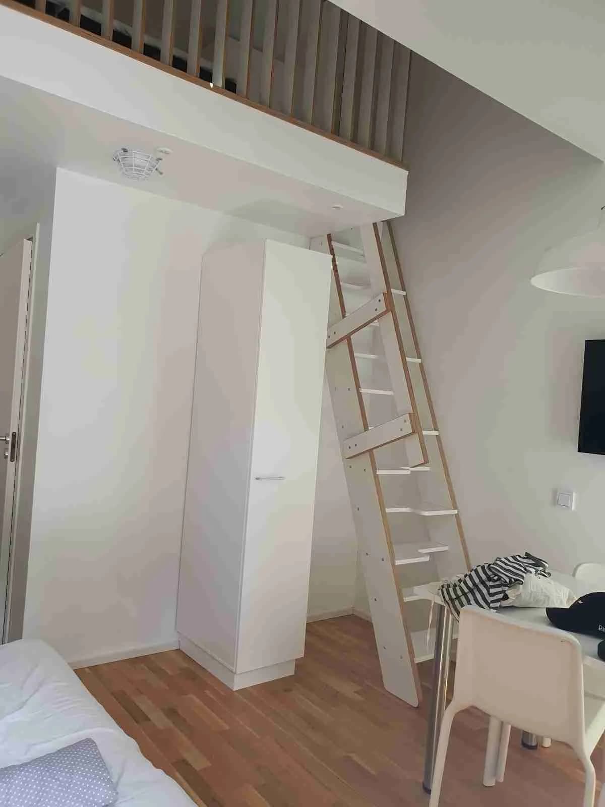 En stuga med trägolv och trätak, inredd med en säng och enkla möbler.