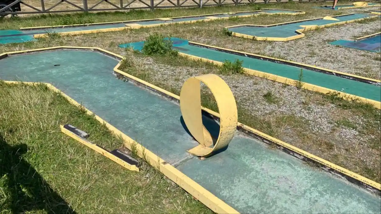 Alt-text: Ett område på Lomma camping med konstgräs där besökare kan spela minigolf och njuta av rekreation i en parkmiljö.