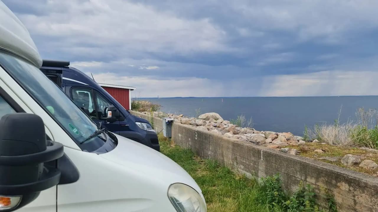 En campingbil parkerad vid Valjevikens camping med utsikt över havet, omgiven av andra bilar och campingfordon.