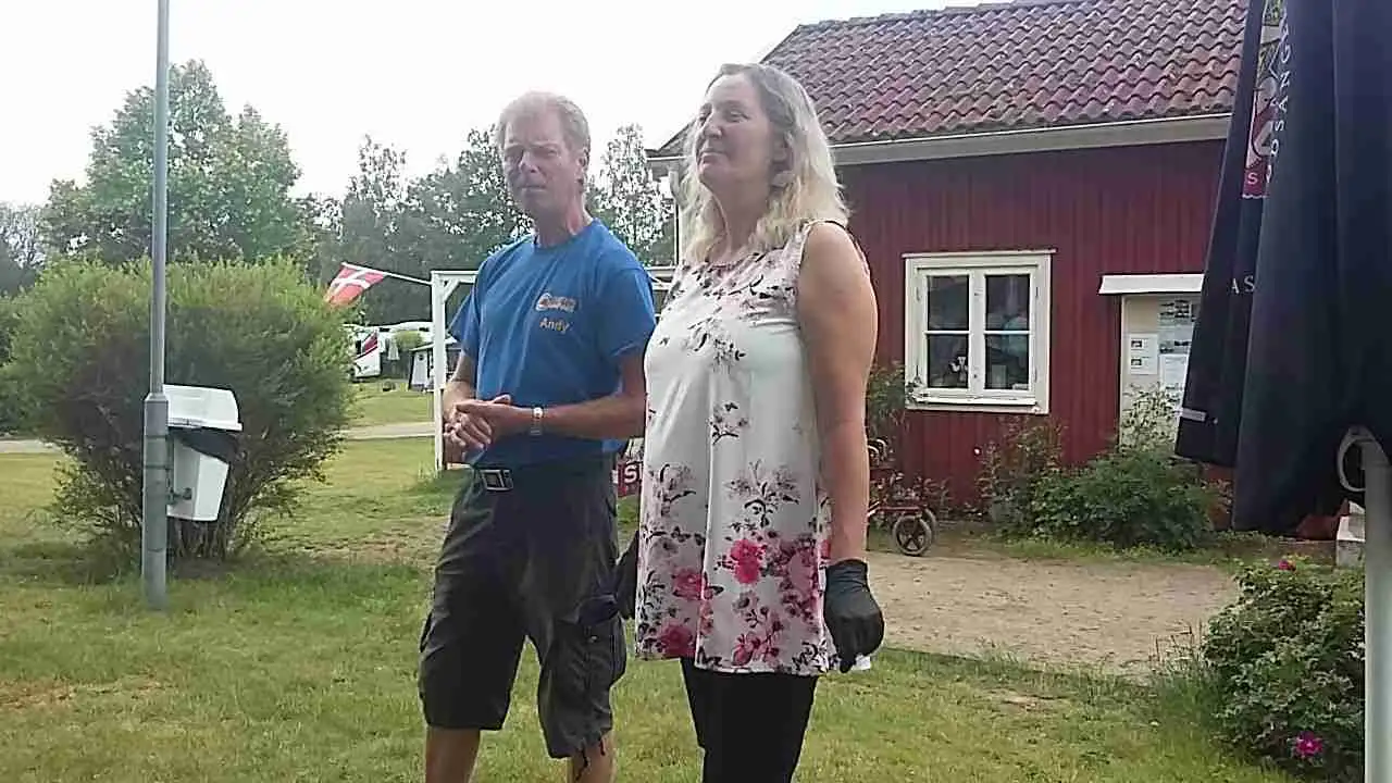 En solig sommardag på Linneryds camping med en grönskande gräsmatta, människor som njuter av fritid och avkoppling i en avslappnad och naturskön miljö.