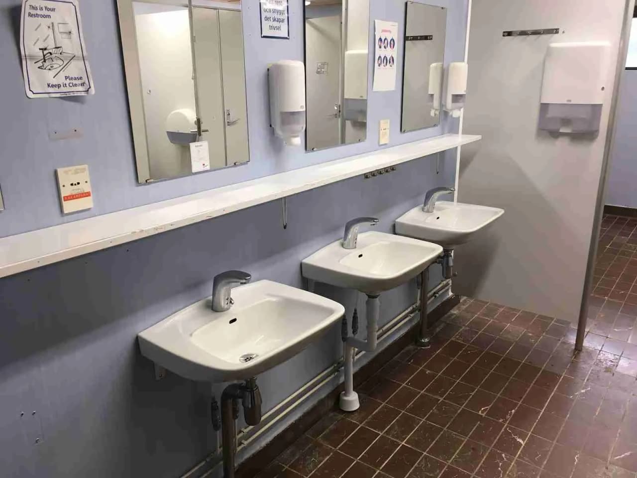 Alt-text: Ett ljust och modernt badrum på Hede Camping med handfat och kran, kaklat golv och väggar, inslag av hygienartiklar samt andra VVS-armaturer.