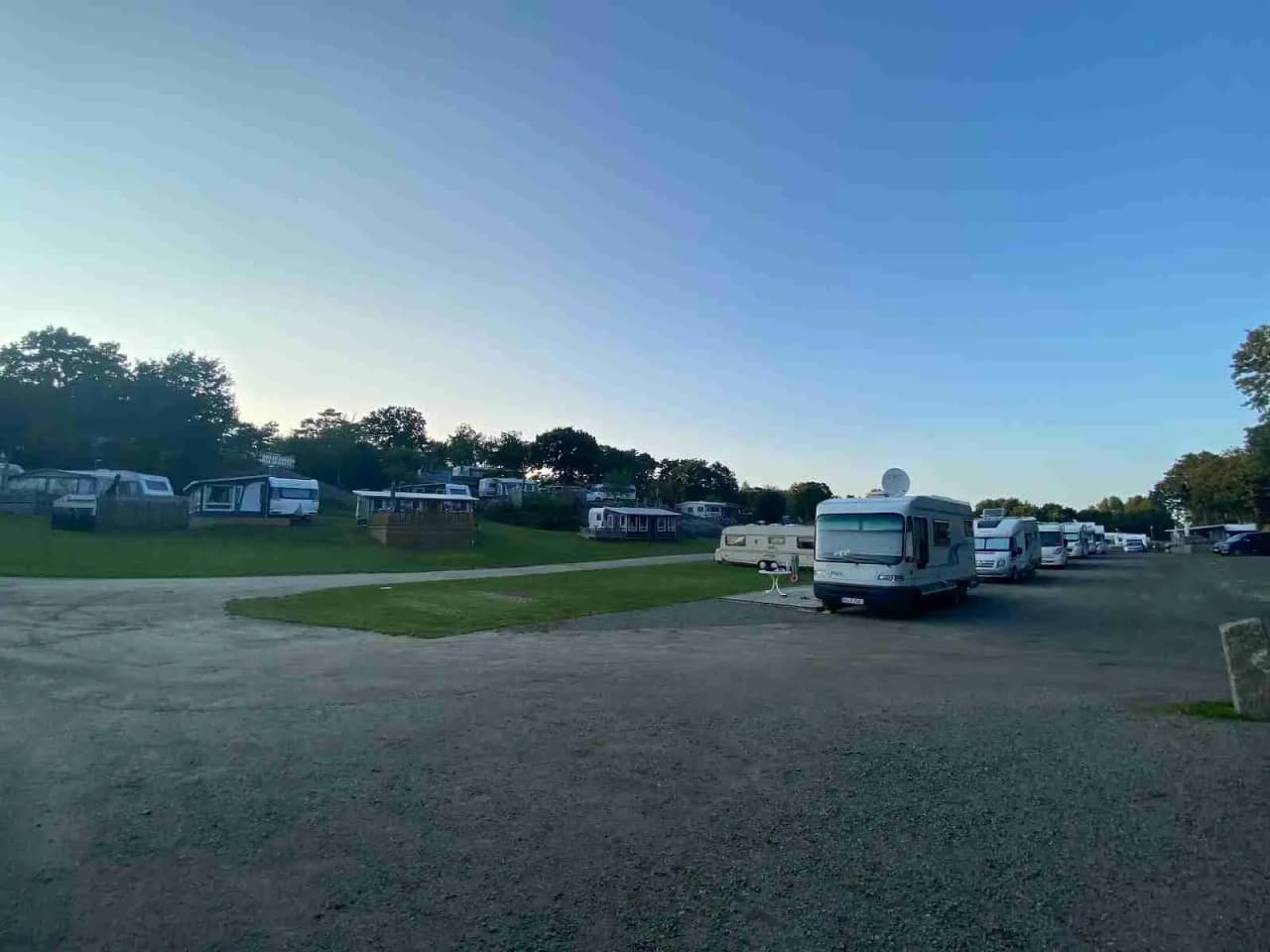En campingplats under en molnig himmel med husvagnar och husbilar parkerade på asfalterade ytor.