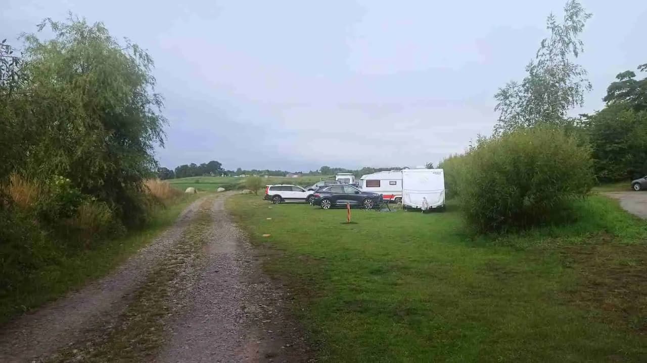 En husbil och en bil parkerade på en öppen gräsplan vid Fredriksbergs kursgård-camping.