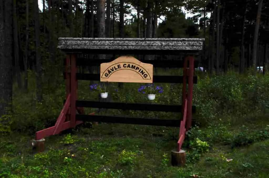 En skylt står bland träden i ett naturskönt skogsområde vid Gävle Camping Engesberg.