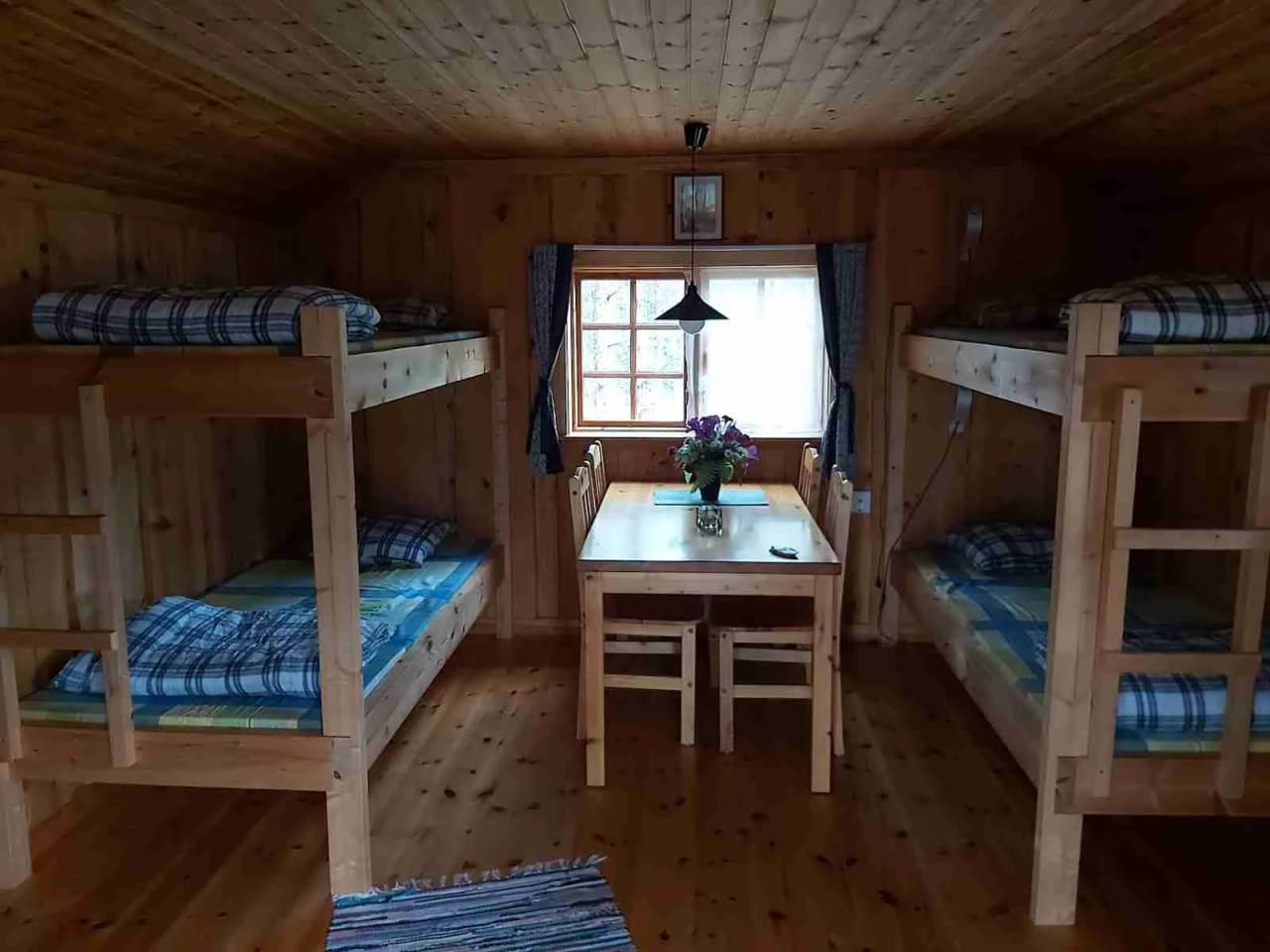 En mysig trästuga med våningssängar och trägolv, typisk för Sörälvens fiske camping & stugby, vilket skapar en varm och rustik atmosfär.