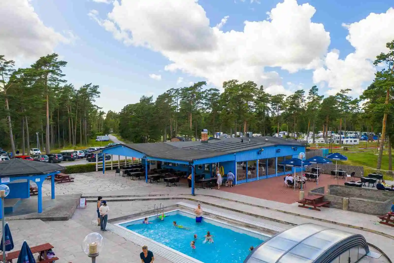 En avslappnande utomhusmiljö vid Åminne Fritid & Havsbad AB, med en pool omgiven av solsängar och parasoller. Perfekt för rekreation och semesteravkoppling nära havet.