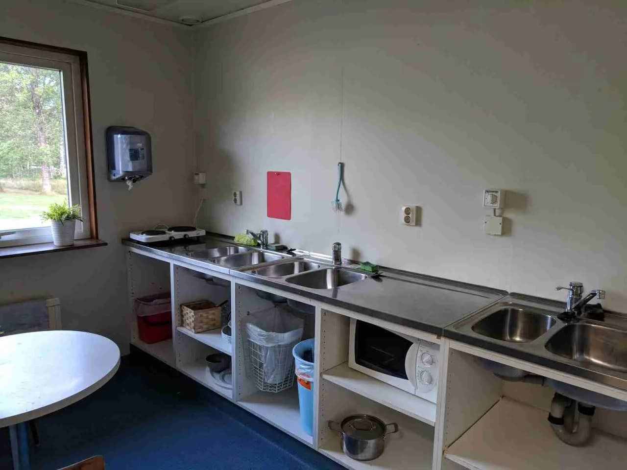 En modern köksdiskho med kran och bänkskiva på ett campingkök, omgiven av köksapparater och möbelinredning.