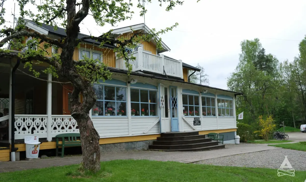 En veranda med utemöbler under tak, omgiven av en grön gräsmatta. Perfekt för avkoppling och semester vid Sofielund vandrarhem & camping.