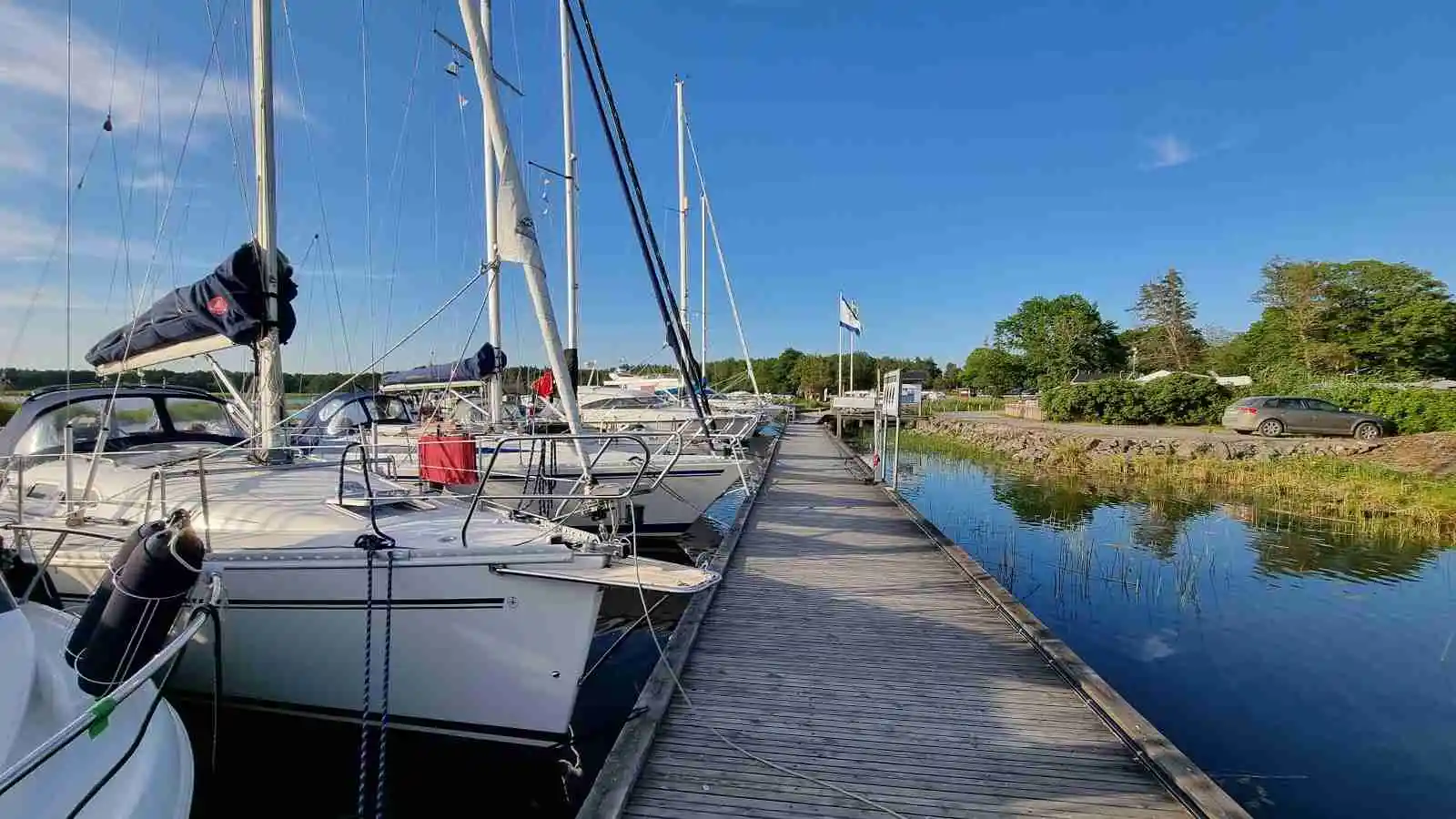 Bild av Ekenäs gästhamn & camping, med flera båtar förtöjda vid bryggan. Mast och båtutrustning syns tydligt, medan vattnet och de närliggande vattenvägarna skapar en inbjudande atmosfär för besökare vid hamnen.