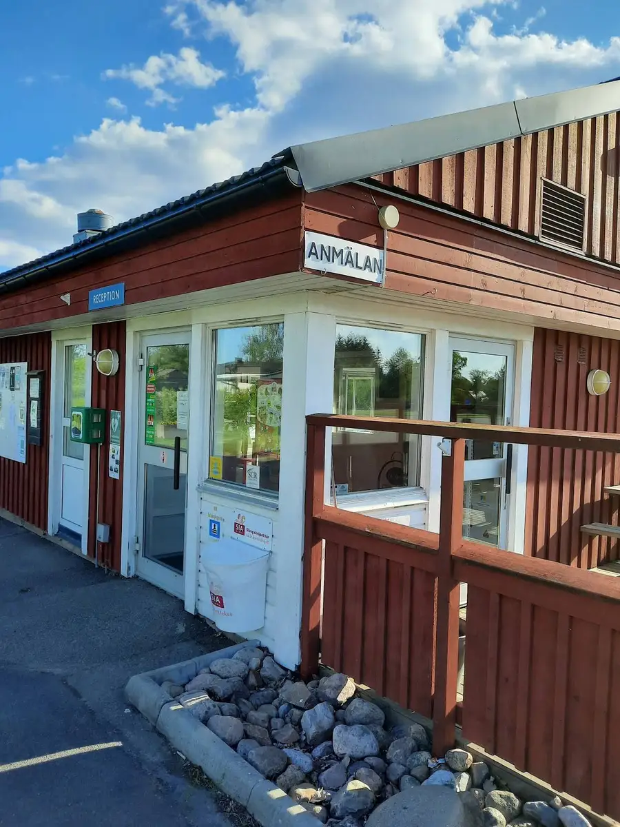 En dörr på en byggnad med liggande träpanel på ett campingområde.