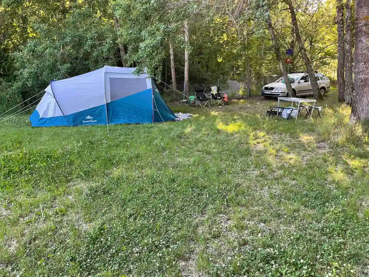 Ett naturskönt campingområde på Ängby Camping, där tält är uppsatta bland lummig grönska och träd. Campingutrustning är synlig i en parkmiljö som inbjuder till rekreation och friluftsliv.
