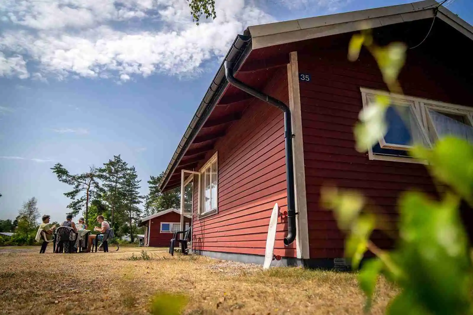En mysig timmerstuga omgiven av grönska och trädgårdsbyggnader på Haga Park Camping & Stugor. Perfekt för avkopplande fritidsvistelser.