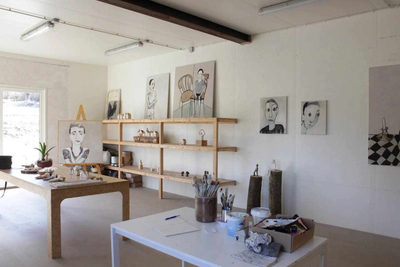 Ett inbjudande interiör av en traditionell pionjärgård med rustik inredning. Rummet har trägolv och hyllor längs väggarna. Möblerna är av naturliga material, inklusive ett skrivbord, och det finns en varm och hemtrevlig känsla i rummet.