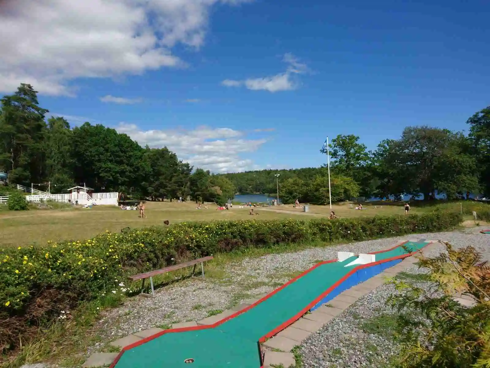 Bilden visar en rekreationspark vid Rösjöbaden Camping & Stugby, med gröna gräsmattor och platser för fritidsaktiviteter. Träd och öppna ytor skapar en inbjudande miljö för besökare.