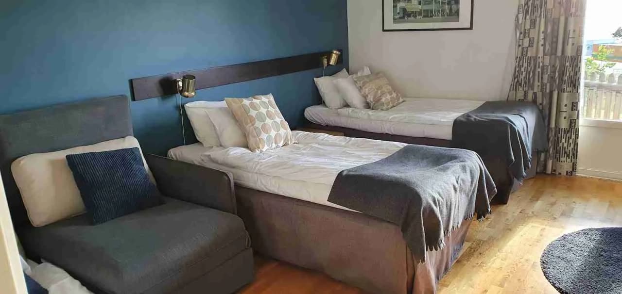 En mysig campingstuga med enkelsängar bäddade med vita lakan. Interiören är enkelt möblerad och golvet har en träfinish.