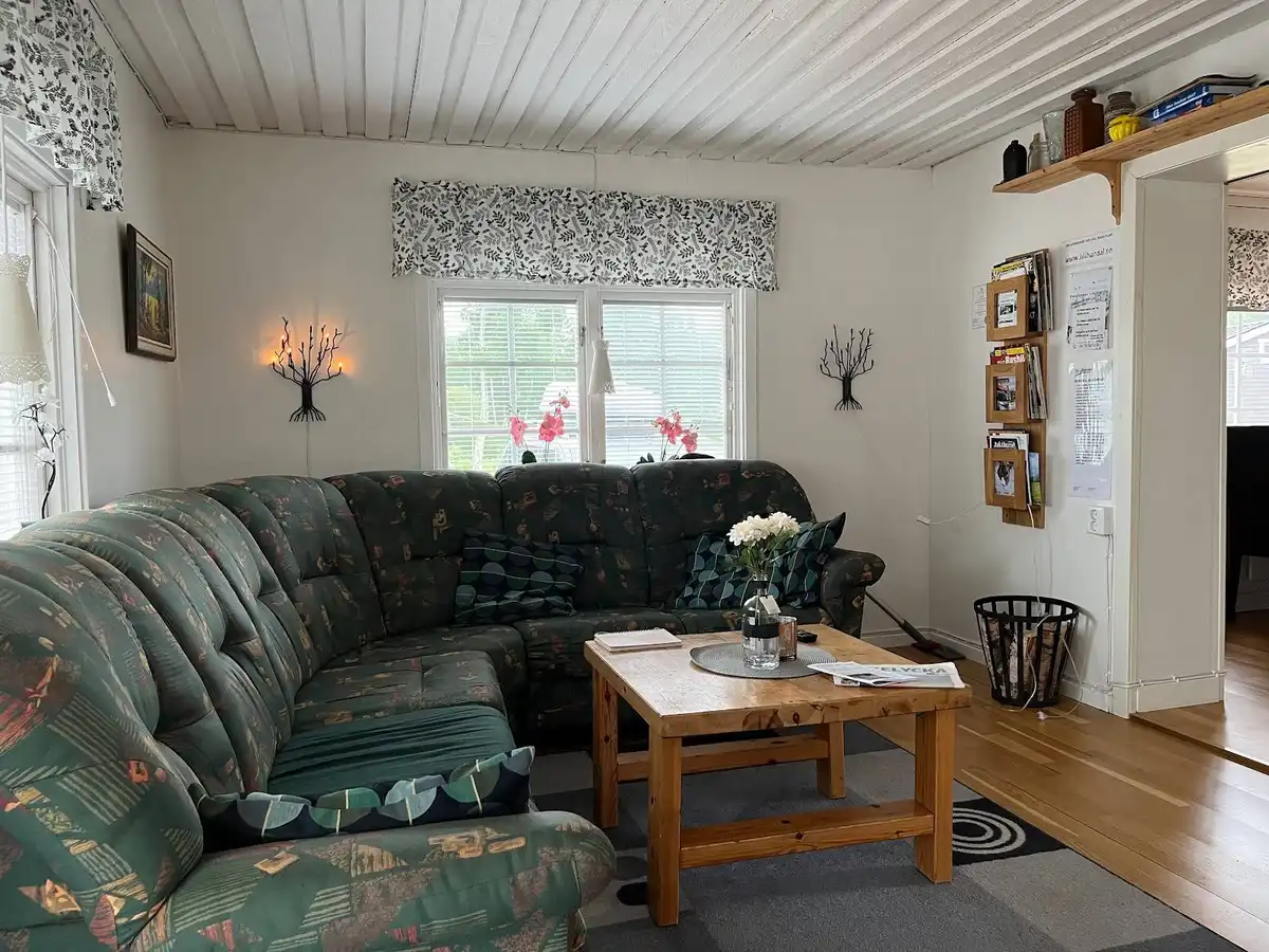 Bild av interiören på Lillhärdals camping. Rummet är inrett med trämaterial och har möbler som en soffa. Golvet är också i trä, vilket bidrar till en hemtrevlig och varm stämning. Takbelysning ger ett behagligt ljus i utrymmet.