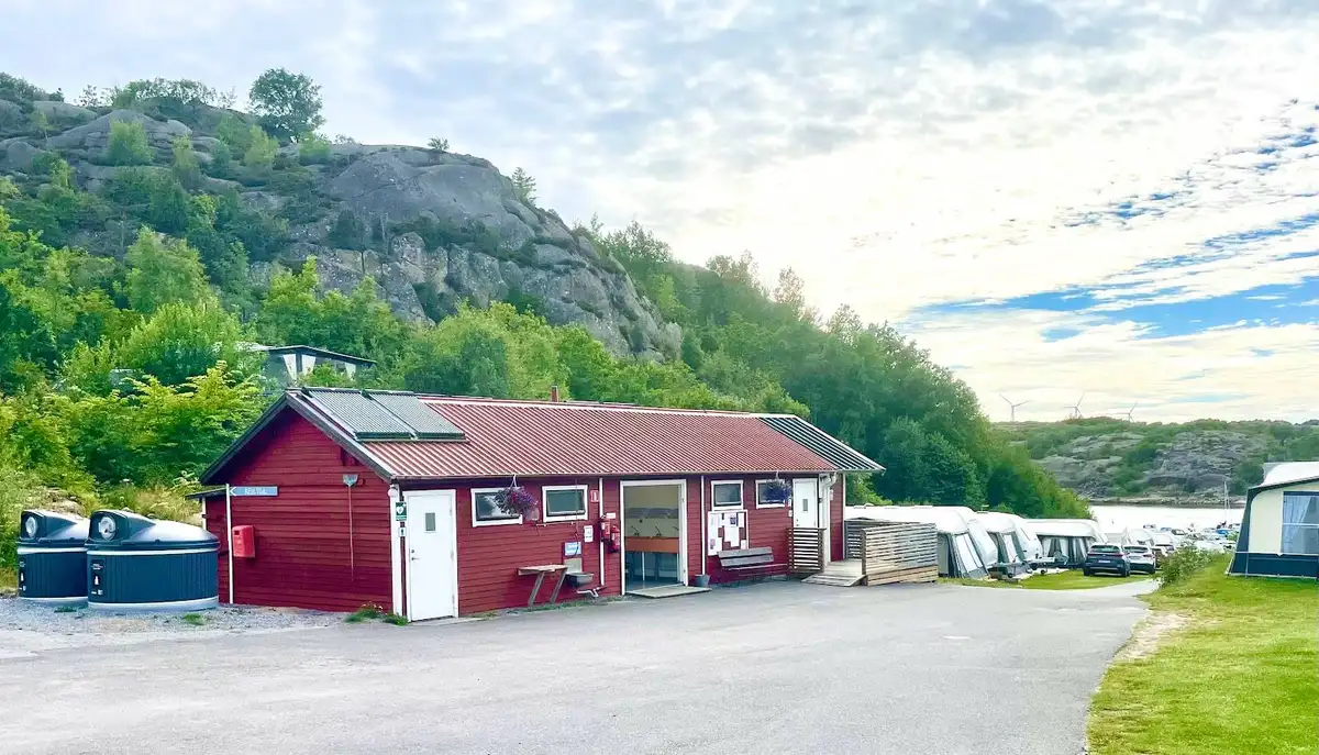 En vy över en kustlinje vid Örns Camping med en båt på vattnet, omgiven av en vik och naturskön miljö.