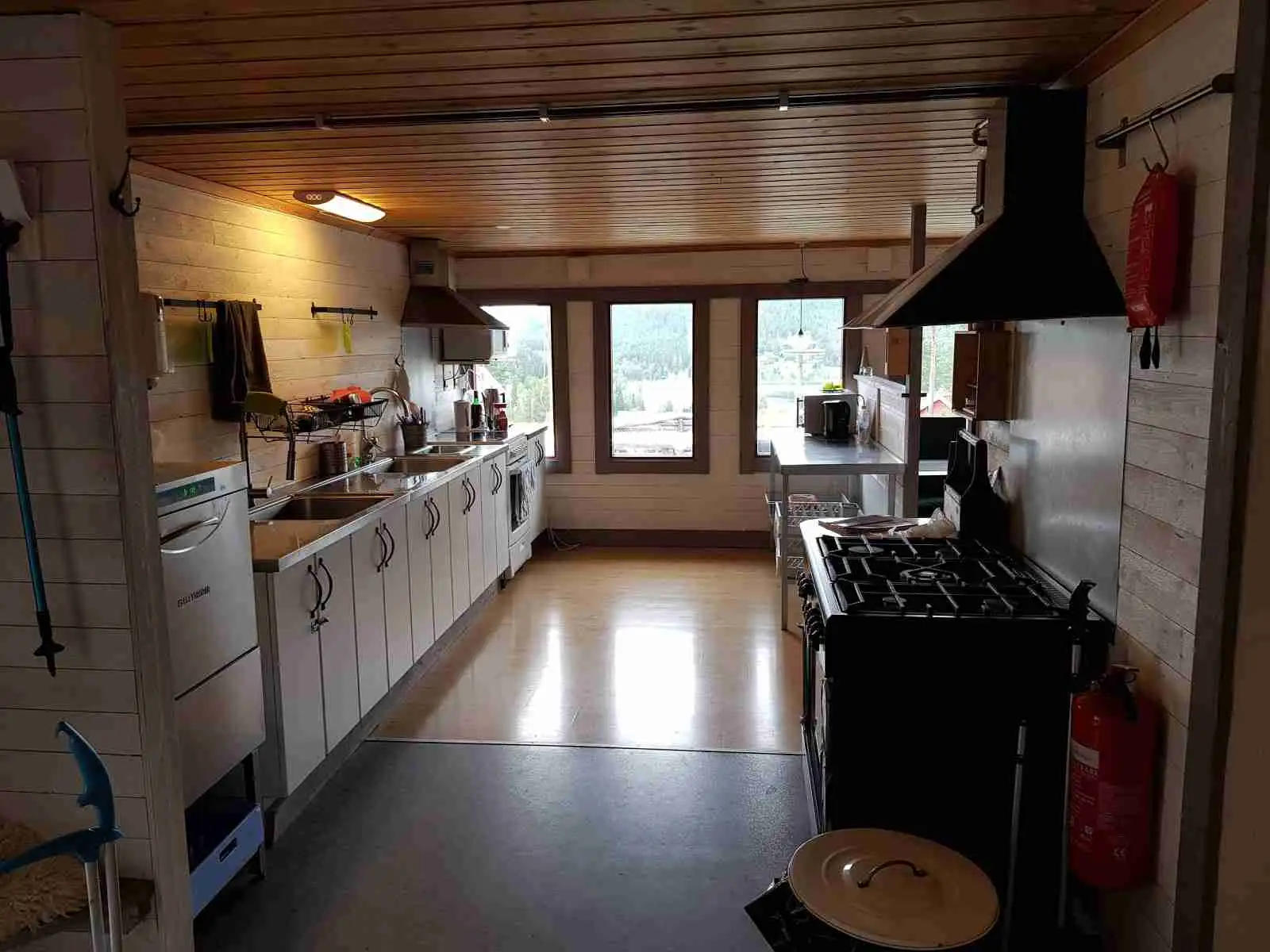 En inbjudande trästuga på Järvsö Bergscamping, med ett välutrustat kök och mysig inredning. Rustika trägolv och tak, tillsammans med bekväma möbler skapar en varm och välkomnande atmosfär.