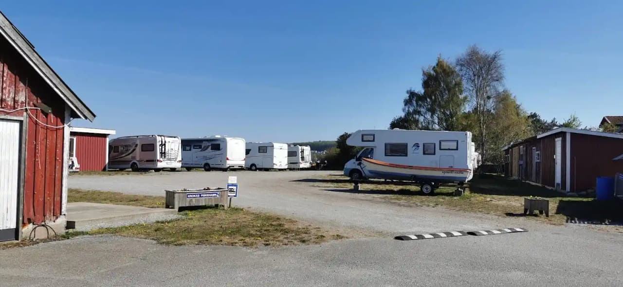 Bild av en campingplats på Valjevikens camping, där flera husbilar och husvagnar står parkerade på en grusplan omgivna av grönska.
